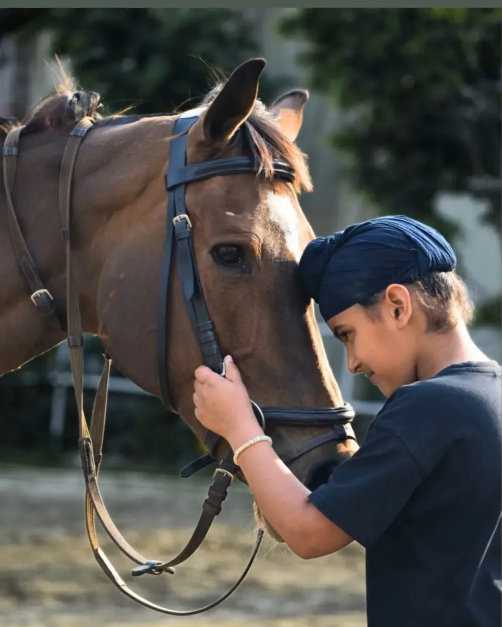 A young rider stands forehead-to-forehead with a horse during a bond-and-groom moment at FHRC.